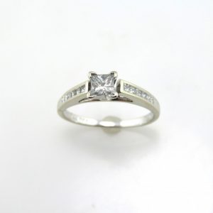Princess cut center diamond in channel set mounting